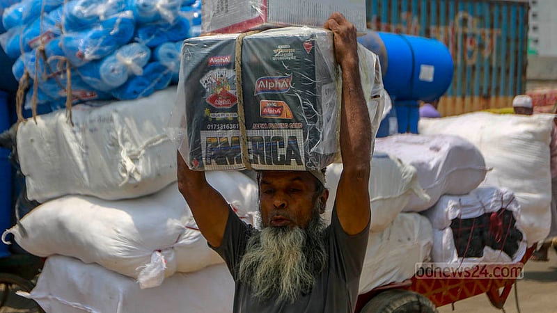 Workers rush to their designated addresses carrying heavy sacks on their heads amidst the scorching afternoon heat on Tuesday, Jun 6, 2023. Photo: Tawhiduzzaman Tapu