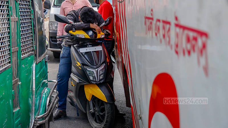 A man tries to nap while waiting on his motorcycle amid intense heat as Gono Odhikar Parishad's march to the Election Commission headquarters brought traffic to a standstill at the Bangla Motor intersection in Dhaka on Tuesday, Jul 25, 2023. Photo: Mahmud Zaman Ovi