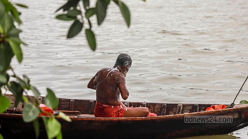 A boatman takes a bath on his boat while floating along the Buriganga River. Photo: Tawhiduzzaman Tapu