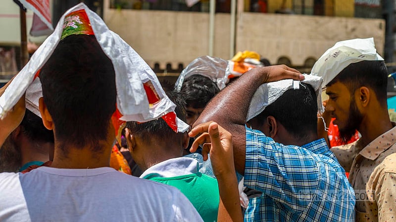 People queuing behind an OMS truck in Dhaka’s Mohammadpur hold shopping bags over their heads to get some respite from the blazing sun on Sunday, Jul 23, 2023. Photo: Tawhiduzzaman Tapu