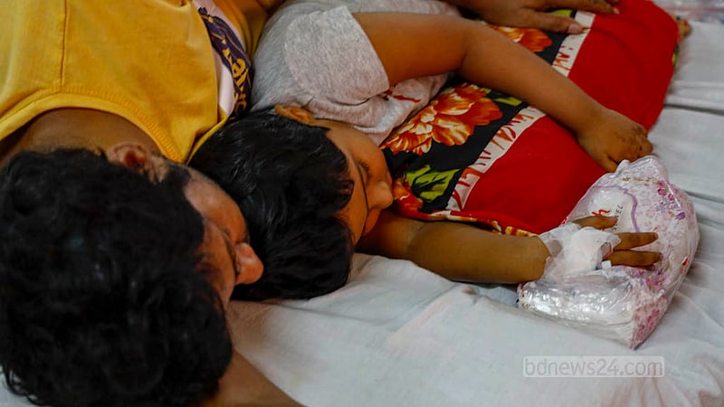 A man lies beside his child, who is suffering from dengue fever, at the capital’s Dhaka Shishu Hospital. Photo: Mahmud Zaman Ovi