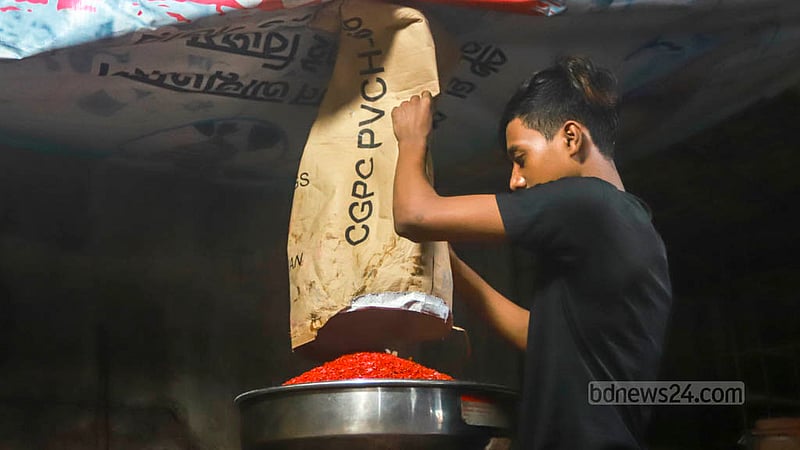 A worker at a Kamrangichar factory pours granules of old plastic into a machine to create new plastic baskets. Photo: Tawhiduzzaman Tapu