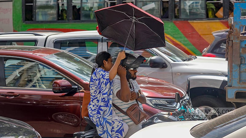 Motorcycle riders take shelter under an umbrella to protect themselves from intense heat as Gono Odhikar Parishad's march to the Election Commission headquarters brought traffic to a standstill at the Bangla Motor intersection in Dhaka on Tuesday, Jul 25, 2023. Photo: Mahmud Zaman Ovi