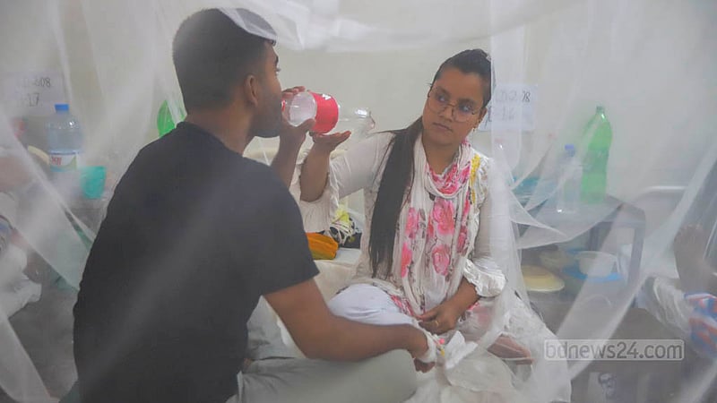 A person is feeding her dengue-infected family member inside a mosquito net at Shaheed Suhrawardy Medical College Hospital in Dhaka. Photo: Tawhiduzzaman Tapu