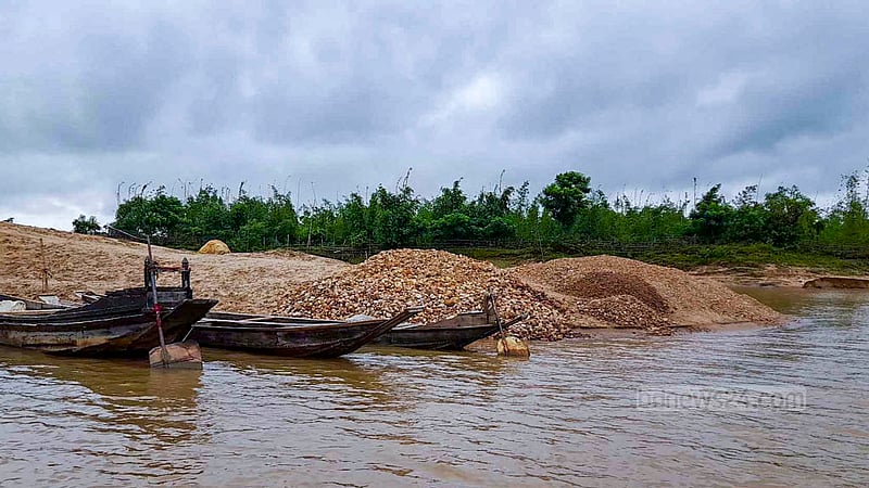 Pebbles, sand, gravel and rocks are extracted from the Jadukata River by illegal dredging machines and then piled on the banks of the river for later collection.