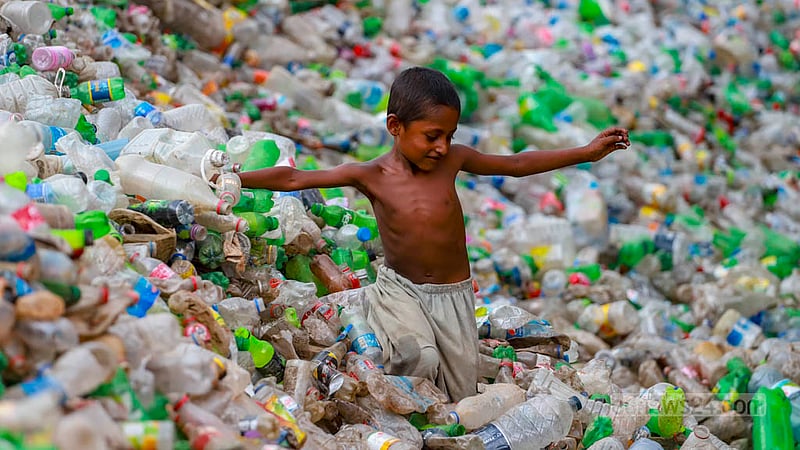Rayhan, a boy who gave a single name, plays in a pile of plastic bottles at a recycling plant where his mother works in Dhaka’s Hazaribagh.  Photo: Tawhiduzzaman Tapu