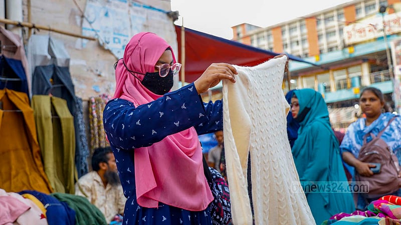 A woman buys winter clothes from the footpath outside the New Market.women. Photo: Mahmud Zaman Ovi