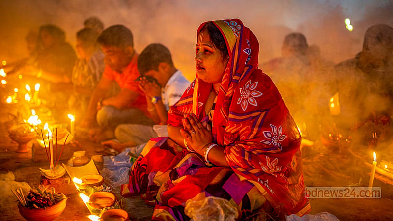 A female disciple of Baba Lokenath Brahmachari prays after lighting lamps at the end of Rakher Upobash or Kartik Broto festival at Barodi Lokenath Ashram in Narayanganj on Saturday, Nov 11, 2023.
