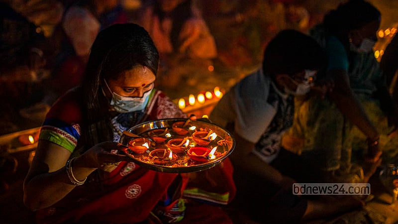 A female disciple of Baba Lokenath Brahmachari prays after lighting lamps at the end of Rakher Upobash or Kartik Broto festival at Barodi Lokenath Ashram in Narayanganj on Saturday, Nov 11, 2023.