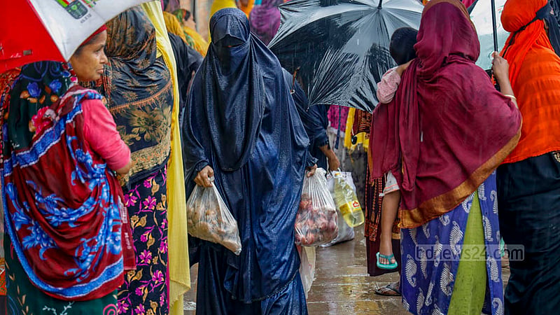A woman soaked in the rain buys goods from a TCB truck in Hatirjheel’s Madhubagh section on Thursday, Dec 7, 2023.