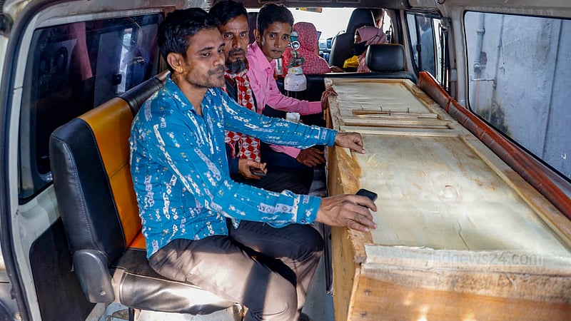 The body of Nadira Akhtar Poppy, prepared for her final journey from the Dhaka Medical College Hospital morgue, is being transported to Netrokona in an ambulance while her husband, Mizanur Rahman, sits next to the coffin.