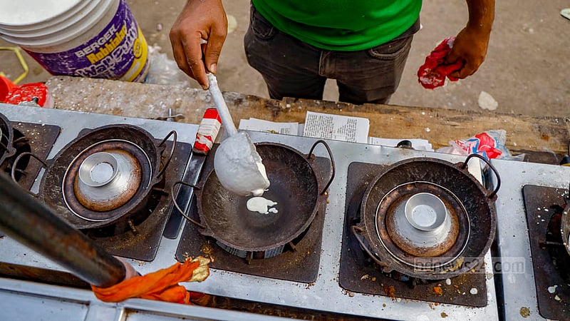 A vendor bakes Chitoi Pitha at a street food shop in Dhaka’s Farmgate.