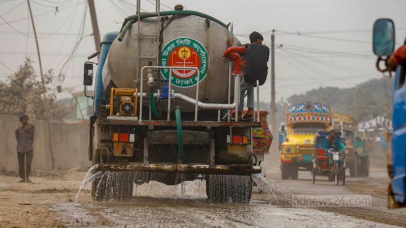 Dhaka North City Corporation workers spray water from a vehicle to  keep dust from mixing with the air in Gabtoli.