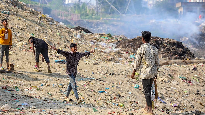 Children are playing next to a pile of burning plastics without protection from the toxic fumes, risking their health.