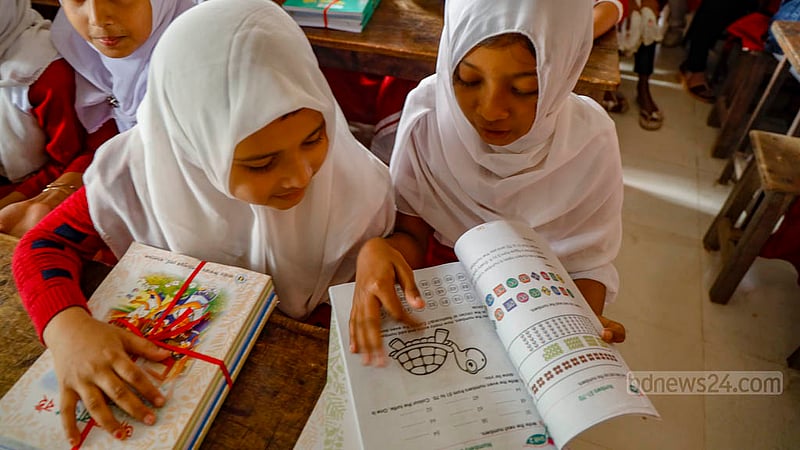 Nusrat Fatema and Sheikh Suraiya, third graders at Raydakkhin Government Primary School in Manikganj’s Singair Upazila, start reading their new textbooks just after they got hold of them in the morning.