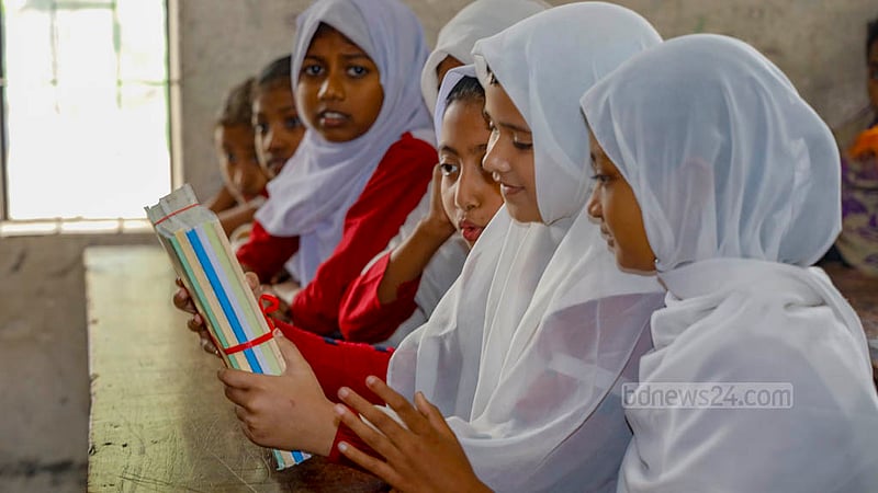 A student of Raydakkhin Government Primary School in Manikganj’s Singair Upazila was in a hurry to open the books tied with colourful ribbons after receiving them on Monday, Jan 1, 2024.
