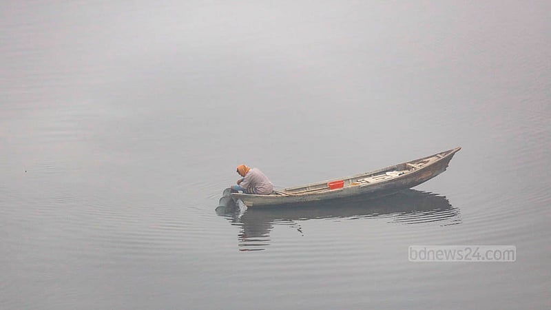 A man uses the illegal China net for fishing on a boat on the Dhaleshwari River amid the dense morning fog.