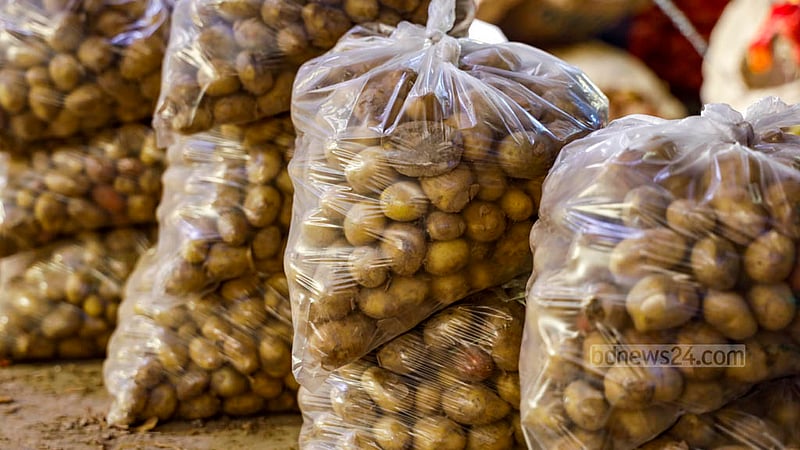 In Dhaka's Karwan Bazar, a trader is seen sorting potatoes into single-use transparent polythene bags for sale.