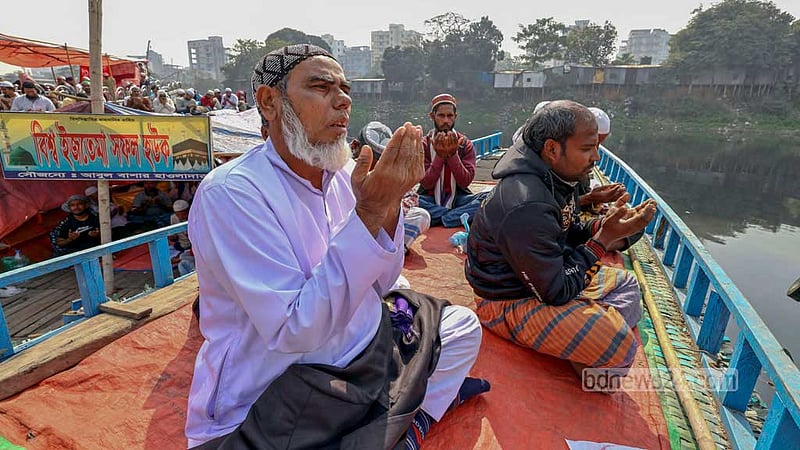 People take part in the Akheri Munajat to close out the second phase of the Bishwa Ijtema from a boat on the Turag River on Sunday, Feb 11, 2024.