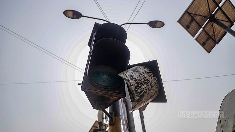 A broken traffic light dangles from the frame outside a mosque in Dhaka.