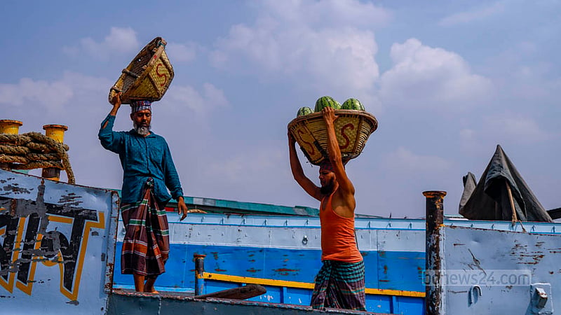 Labourers unload watermelons from vessels at Dhaka’s Waisghat.