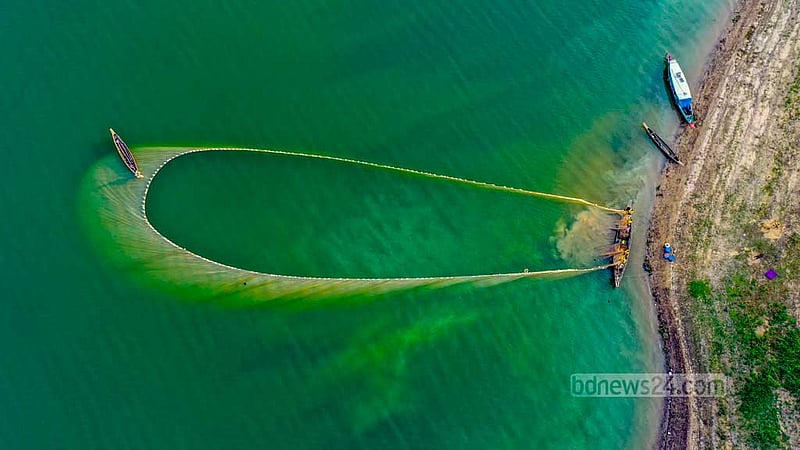 Fishermen use mesh dips in the turquoise waters of Rangamati’s popular fishing spot, Kaptai Lake. Commercial fishing in the lake is banned during the months of May, June, and July to safeguard against overfishing and the potential extinction of carp fish.