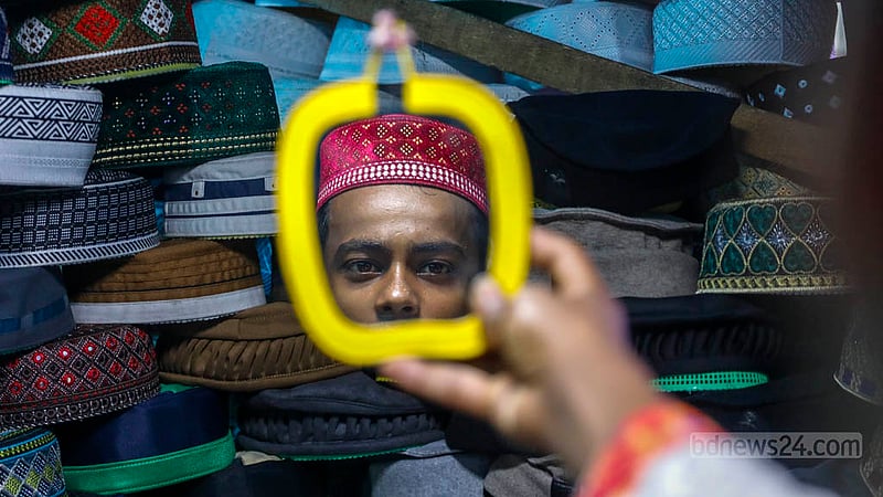 A customer browses caps at a store in front of the Baitul Mukarram National Mosque ahead of Eid-ul-Fitr.
