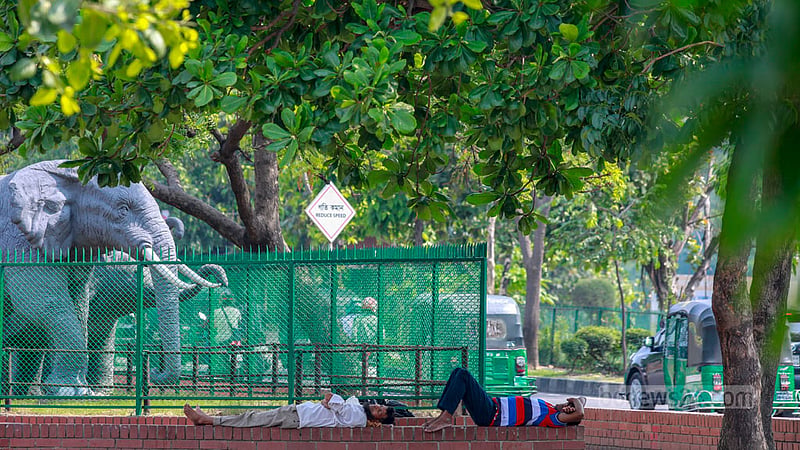 Pedestrians in Dhaka find respite from the scorching sun by taking shelter under the shade of a tree at Hatirjheel on Thursday afternoon, Apr 18, 2024.