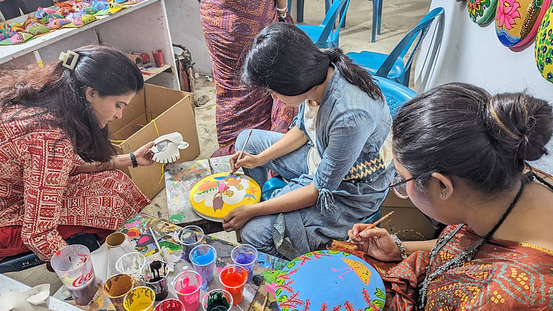 A trio of artists work on painting masks and bowls at the Dhaka University Faculty of Fine Art amid preparations for the Mangal Shobhajatra procession.