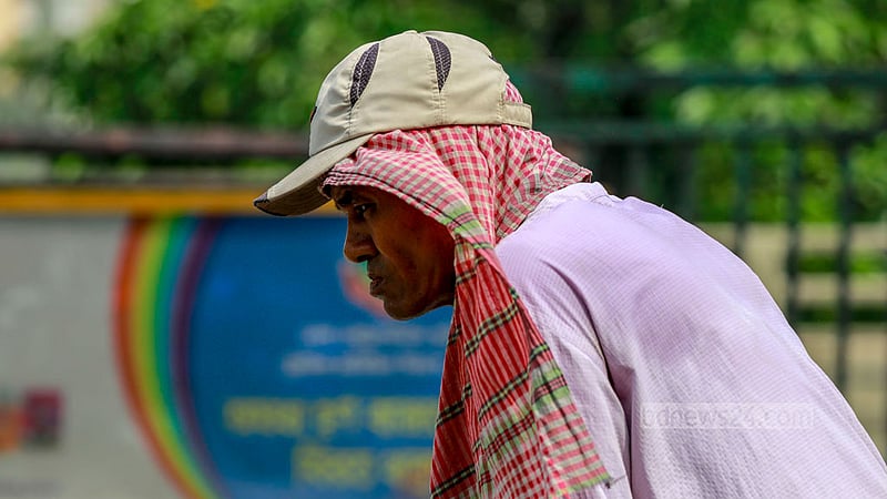 A rickshaw puller in Dhaka shields himself from the blazing sun by covering his head with a towel on a hot afternoon.