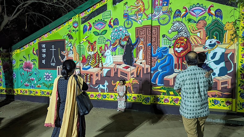 Families take pictures of their children in front of the decorations put up at the Dhaka University Faculty of Fine Art ahead of the Mangal Shobhajatra procession.