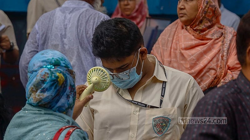 A student takes a brief look at a textbook outside the Siddeshwari Girls’ College centre just before his exam as her mother cools her with an electric fan. Photo: Mahmud Zaman Ovi