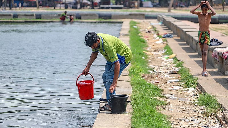 A vendor at Suhrawardy Udyan fills a bucket with pond water to wash plates, bowls, and glasses, despite the unhygienic conditions. Photo: Abdullah al Momin