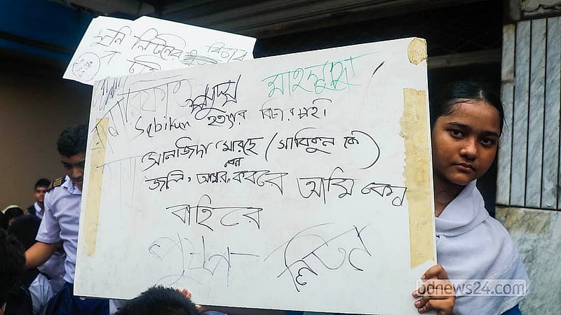 A student holds a placard demanding justice and action against Bright School Founding Chairman Masud Hasan Liton during the demonstration on Thursday, May 21, 2026.  Photo: Abdullah Al Momin
