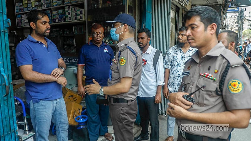 Police officers warn shopkeepers on North South Road against placing goods on the road or pavements. Photo: Abdullah al Momin