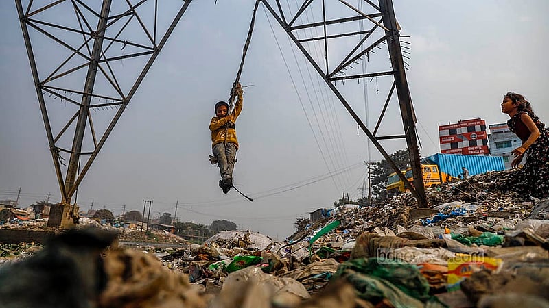 A child swings from a rope tied to an electricity pole beside the iron bridge in Dhaka’s Kamrangirchar, with garbage floating in the Buriganga River below. Photo:  Mahmud Zaman Ovi