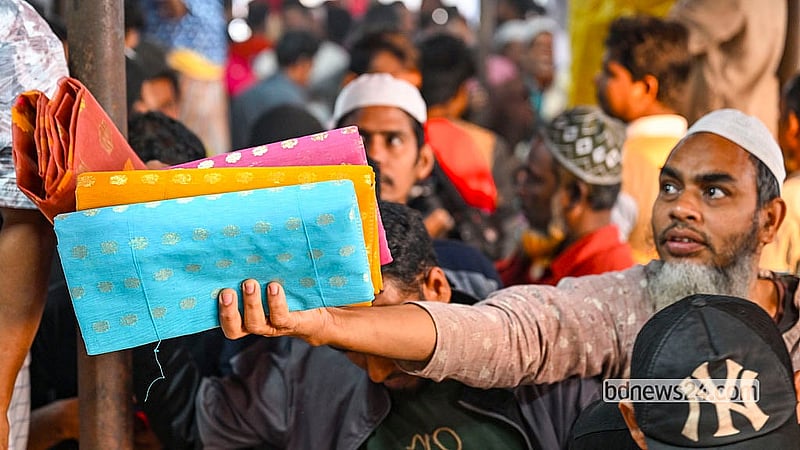 A weaver lifts a sari high, hoping to catch the attention of customers at the bustling Friday market. Photo: Mostafigur Rahman