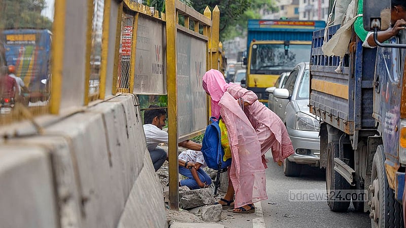 In Dhaka’s Mohakhali, a woman attempts to cross with a child through a small gap under the iron fencing on the divider, despite a foot overbridge being directly overhead. Photo: Mahmud Zaman Ovi