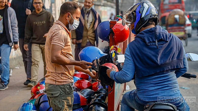 A motorcycle rider pulls over beside a roadside helmet shop at the capital’s Science Lab intersection to look at the items on display. Photo: Mahmud Zaman Ovi