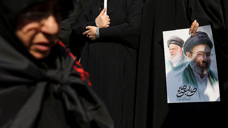 A woman holds an image of Iran's new supreme leader, Mojtaba Khamenei, alongside late Iranian Supreme Leader Ayatollah Ali Khamenei, during a funeral ceremony for the Iranian military commanders who were killed in strikes, amid the U.S.-Israeli conflict with Iran, in Tehran, Iran, March 11, 2026. Photo: Reuters