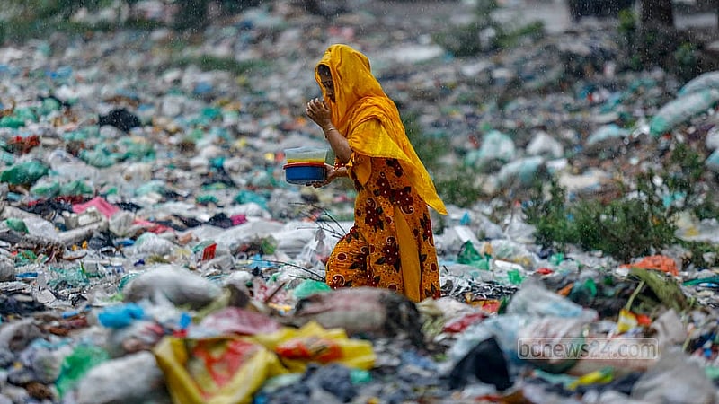 A woman walks across the piles of plastic waste in Shubhadda Canal in Dhaka’s South Keraniganj, while carrying food in the rain. Photo: Mahmud Zaman Ovi
