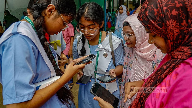 Students of Viqarunnisa Noon School and College check SSC results on mobile phones as the results are yet to arrive at the institution on Sunday, May 12, 2024.