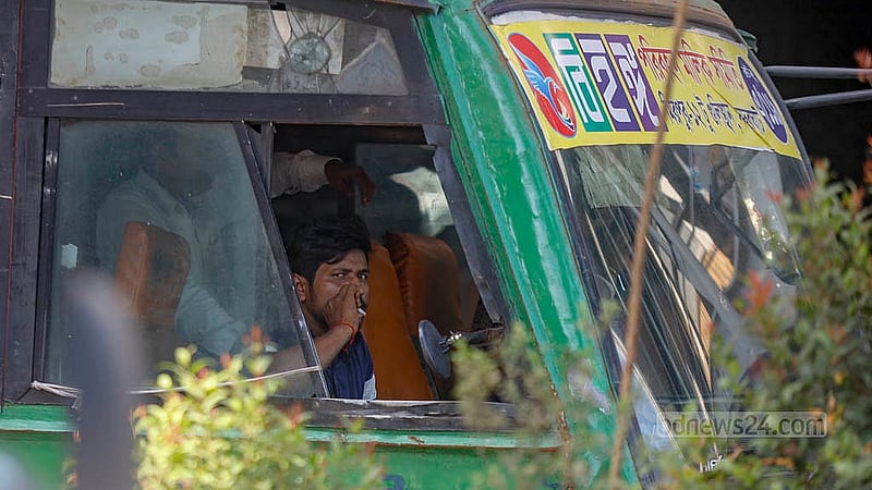 A bus driver smokes at a Bihanga Paribahan bus stationed at a traffic signal at Dhaka’s Karwanbazar intersection on Sunday, Sept 28, 2025. Photo: Mahmud Zaman Ovi