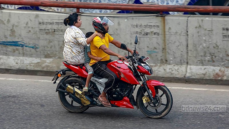 A child is seated at the front of a motorcycle on the busy Moghbazar-Mouchak flyover in Dhaka. The driver is wearing a helmet, but neither the rear passenger nor the child has any safety gear. Photo: Mahmud Zaman Ovi