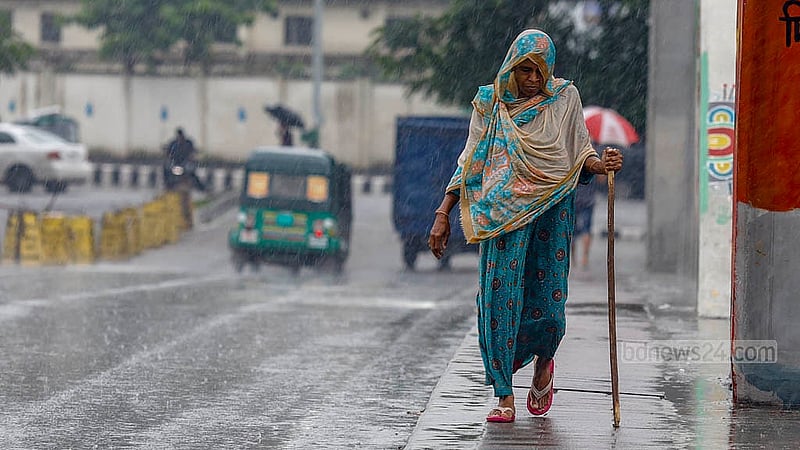 An elderly woman walks with a stick while being drenched in the downpour in Hatirjheel on Sunday noon, Sept 15, 2024. Photo: Mahmud Zaman Ovi