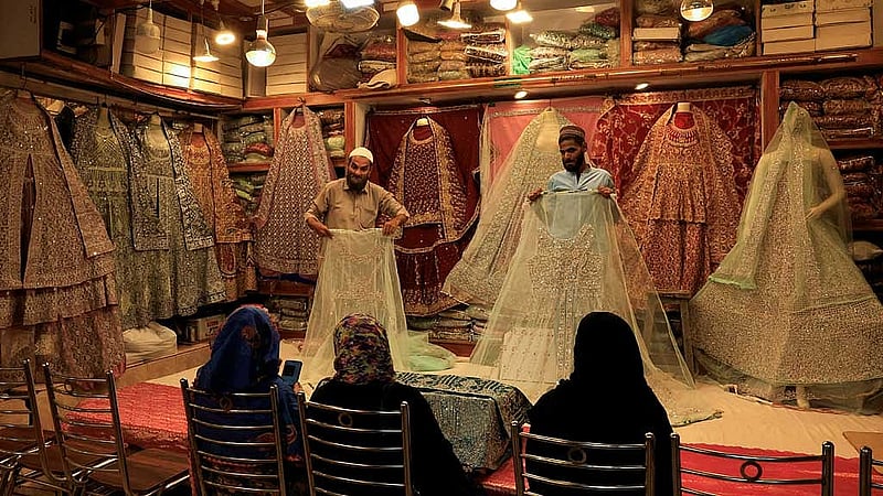 Shopkeepers display bridal dresses to customers at a shop in a cloth market in Karachi, Pakistan Sept 23, 2025. REUTERS