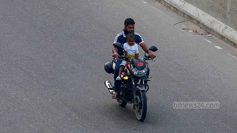 A child is being carried on the front of a motorcycle on the busy Moghbazar-Malibagh flyover in Dhaka. There are no safety measures in place, and the child is not even wearing a helmet. Photo: Mahmud Zaman Ovi
