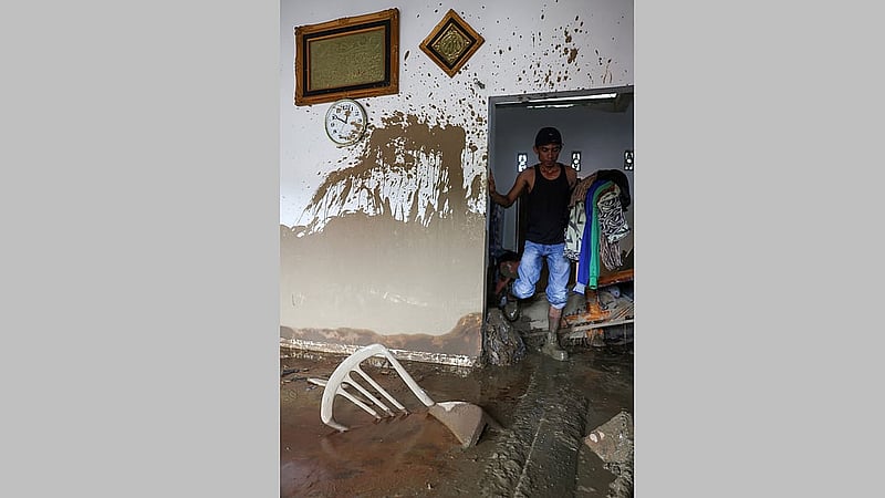 Irza Sarmila, 43, carries valuable goods recovered from his parents' house that was heavily damaged by deadly flash flood in Palembayan, Agam regency, West Sumatra province, Indonesia, Dec 2, 2025. REUTERS/Willy Kurniawan