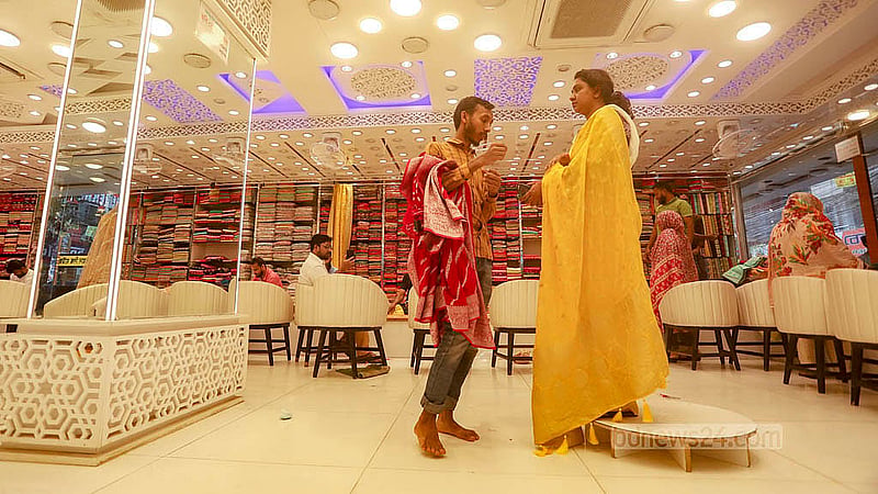 A woman tries on a saree during Eid shopping at the Adi Indian Silk House at Benarasi Palli in Dhaka’s Mirpur. Photo: Abdullah al Momin