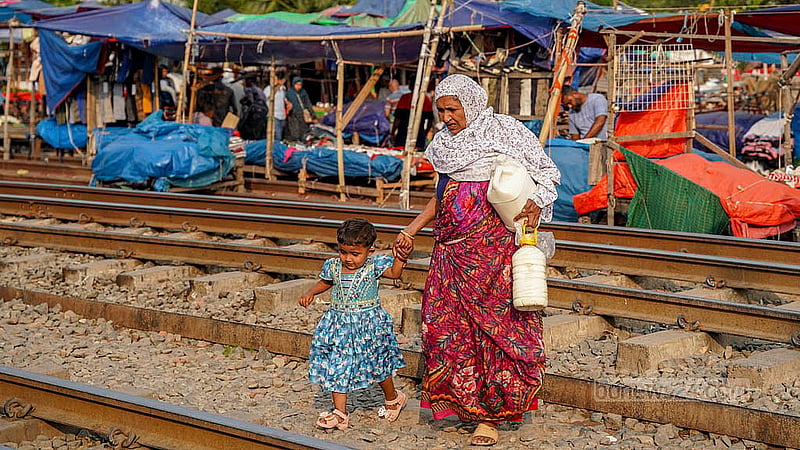 A woman and a child cross the railway track at Dhaka’s Kuril Bishwa Road, even though there is no level crossing. Photo: Tanjinur Rahman Bhuiyan